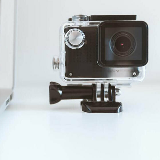 Action camera in a clear waterproof housing on a mounting base.