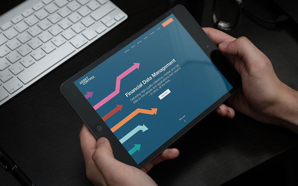 Tablet showing an Asset Control webpage titled “Financial Data Management” with rising arrow charts.