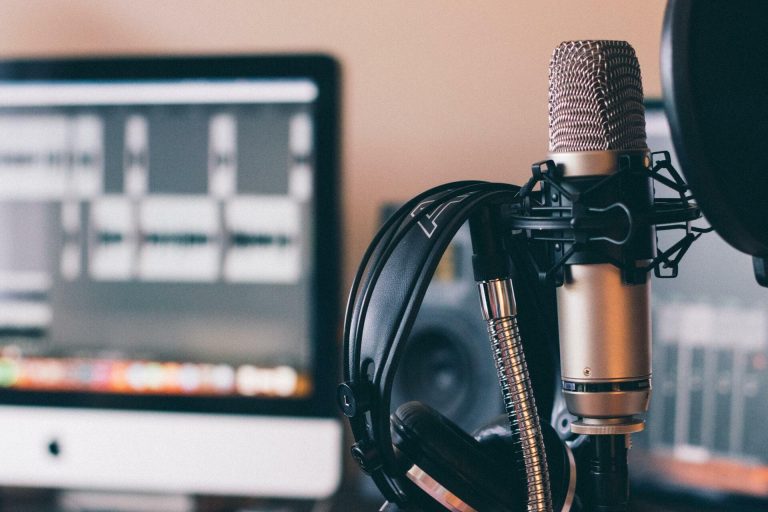 Microphone with headphones in front of a computer in a recording studio