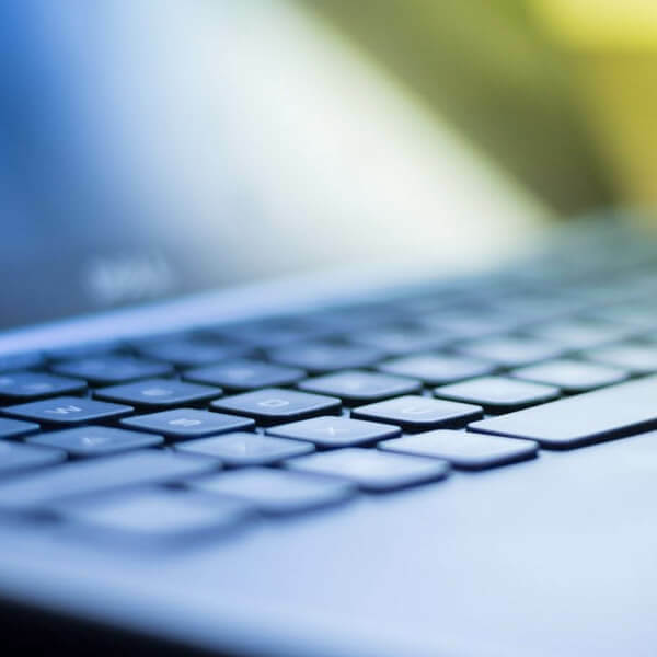 Close-up of a laptop keyboard with soft blue and yellow light in the background.