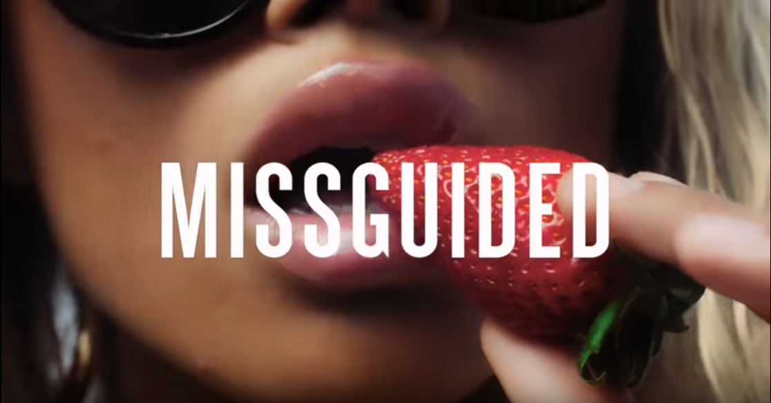 MISSGUIDED text over a close-up of a woman holding a strawberry near her lips.