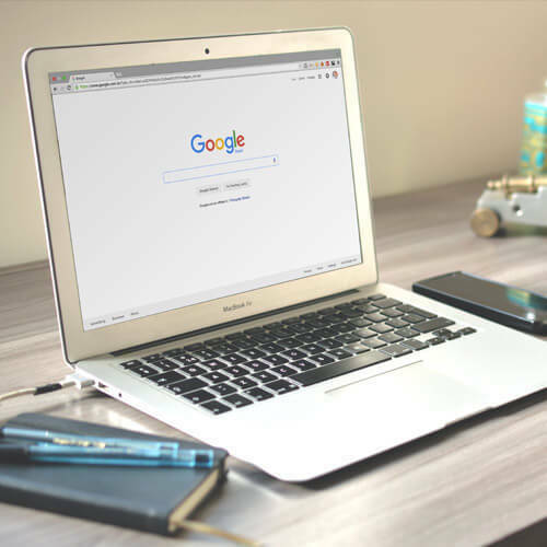 Laptop displaying the Google homepage on a desk.