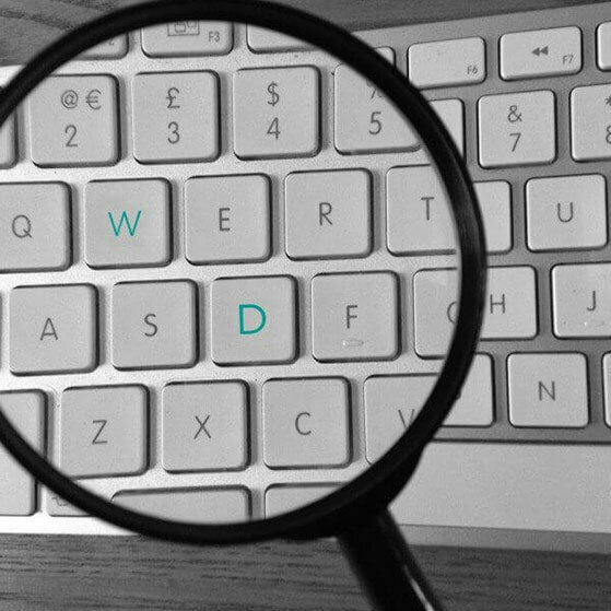 Magnifying glass over a keyboard, highlighting the W and D keys.