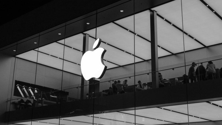 Apple logo on a glass-fronted Apple Store interior.