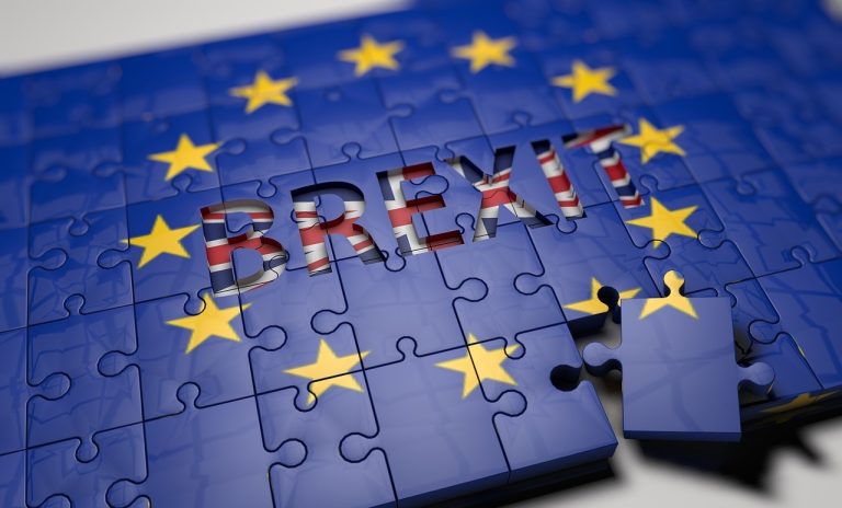 BREXIT spelled across a blue EU flag jigsaw puzzle with yellow stars.