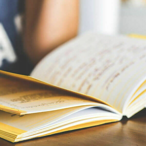 An open book lying on a wooden table with pages mid-turn.