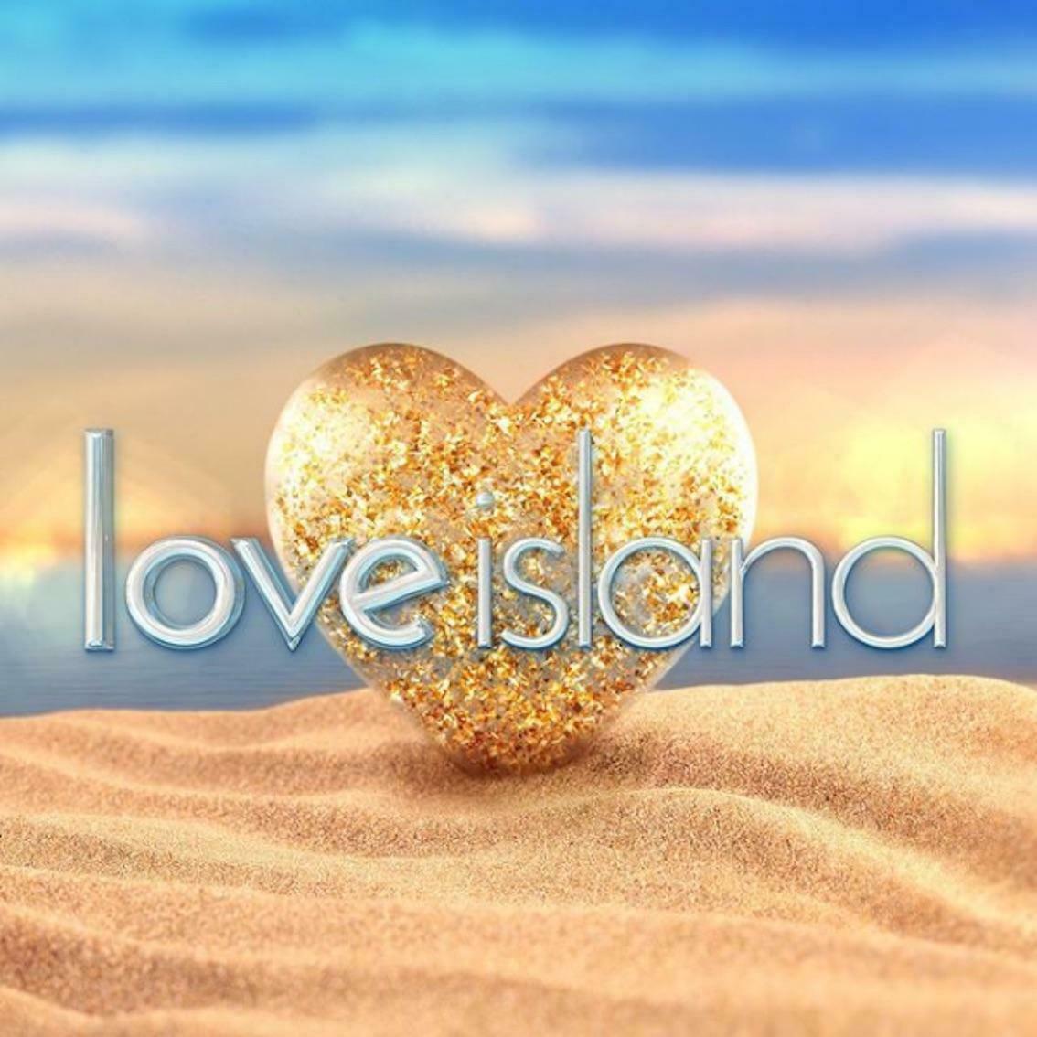 Love Island logo over a glittery heart on a sandy beach at sunset.
