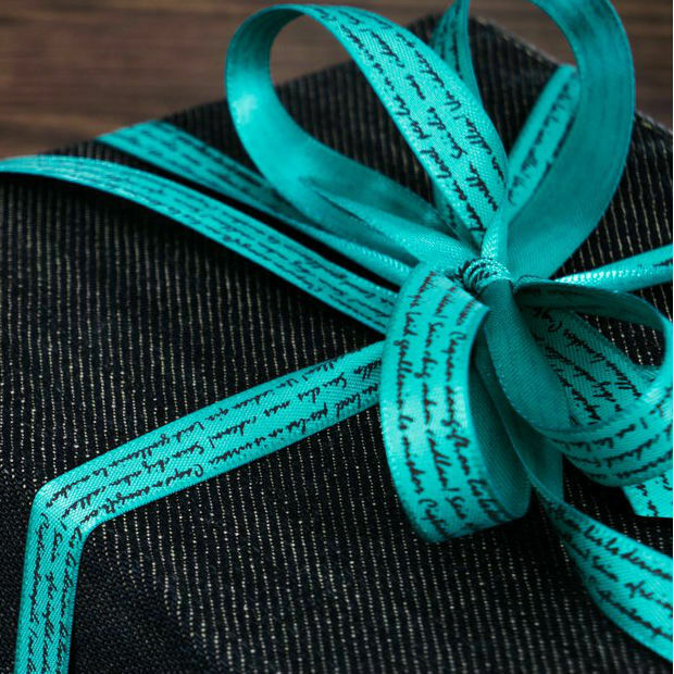 Turquoise ribbon tied in a bow around a wrapped gift box.
