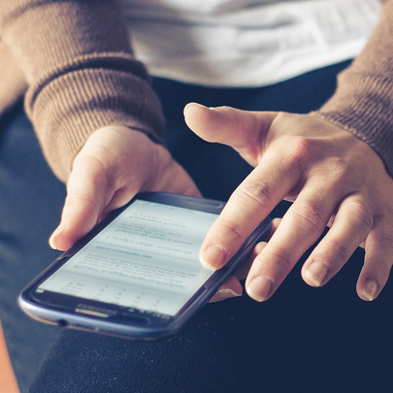 Hands using a smartphone with a messaging or email screen open.