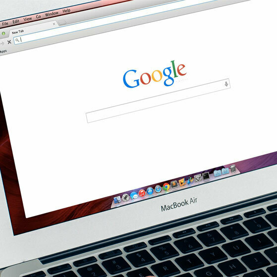 MacBook Air showing the Google homepage in a browser window.