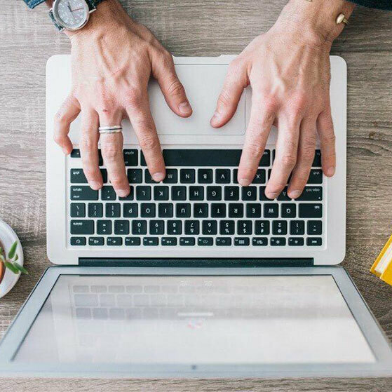 Hands typing on a laptop keyboard