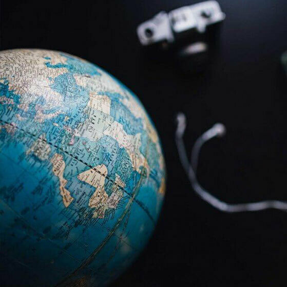 Globe with blurred camera and earbuds in the background.
