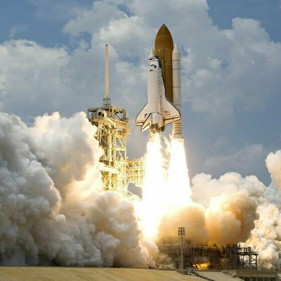 Space shuttle launching with bright exhaust and billowing smoke.