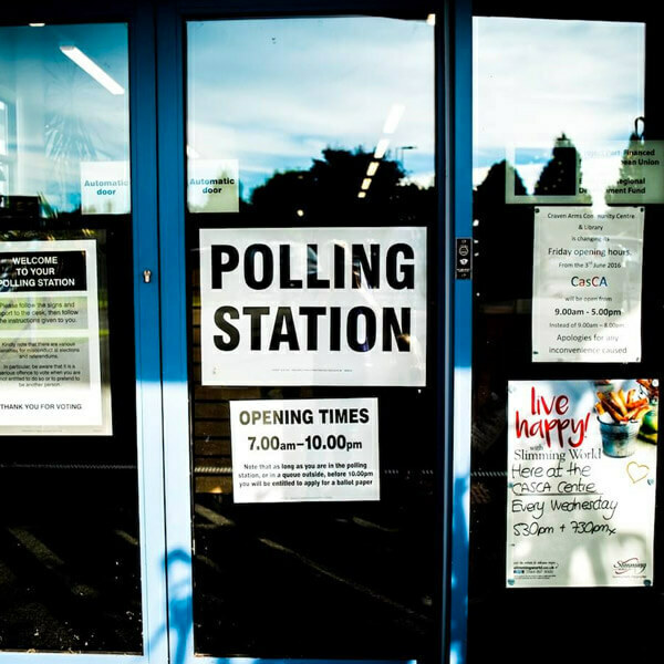 Polling station entrance with signs for opening times, 7.00am–10.00pm.