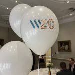 White balloons printed with the WP 20 logo at a formal event table.
