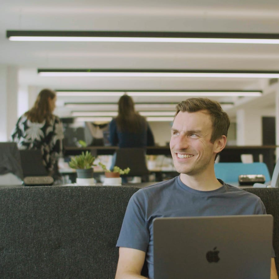 Smiling man working on a laptop in a modern office.